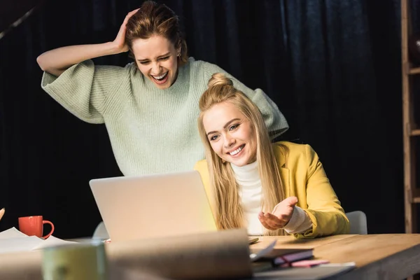 Bela fêmea ele especialistas rindo ao usar laptop no escritório — Fotografia de Stock