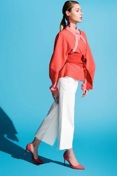 Attractive fashionable woman posing in living coral clothing on blue — Stock Photo