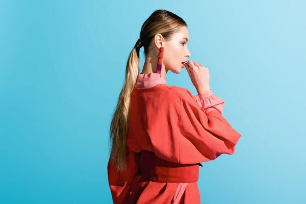 Beautiful stylish girl posing in trendy living coral clothing isolated on blue — Stock Photo