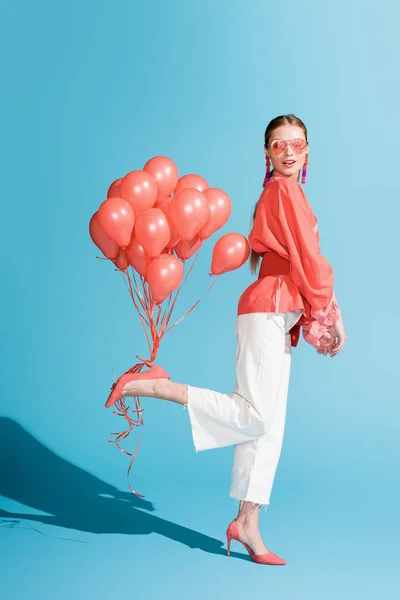 Modello alla moda in posa con palloncini di corallo viventi su blu — Foto stock