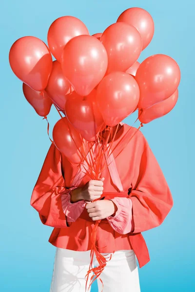 Stylish girl posing with living coral balloons in front of the face isolated on blue — Stock Photo