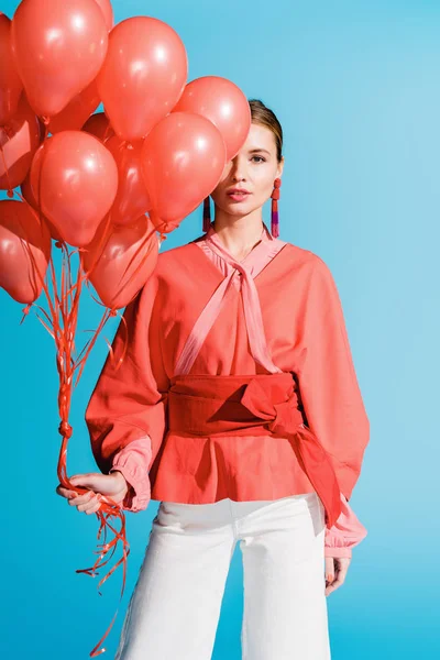 Chica de moda posando con globos de coral vivos aislados en azul - foto de stock