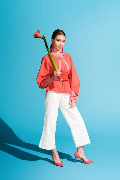 Fashionable elegant girl holding living coral flower on blue. Pantone color of the year 2019 concept — Stock Photo