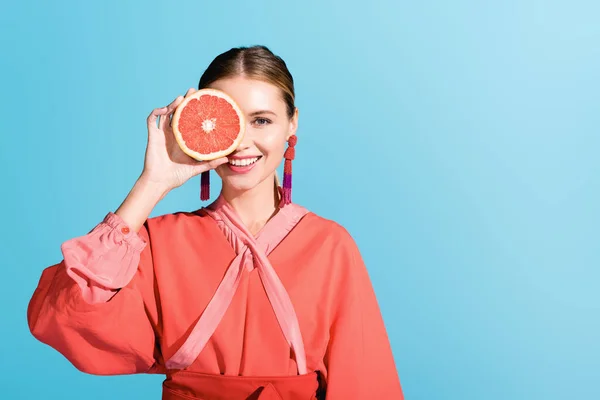 Séduisant modèle heureux en vivant corail posant avec pamplemousse isolé sur bleu — Photo de stock