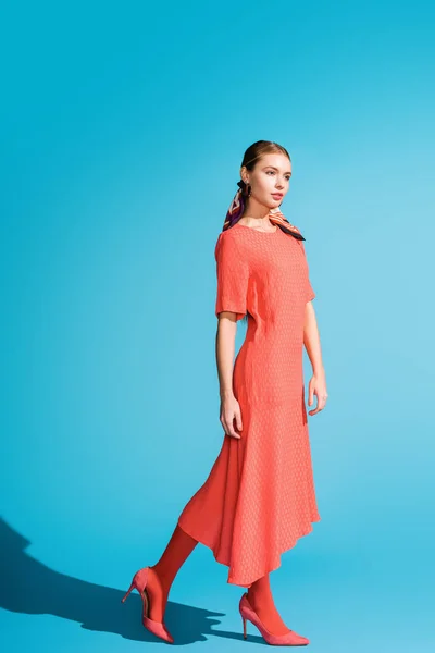 Красива модна дівчина в модній живій кораловій сукні позує на синьому — стокове фото