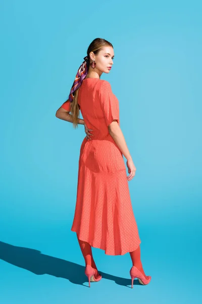 Attractive stylish girl in trendy living coral dress posing on blue — Stock Photo