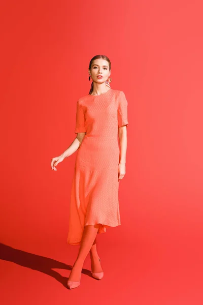 Attrayant élégant fille posant dans la robe de corail vivant sur fond rouge — Photo de stock