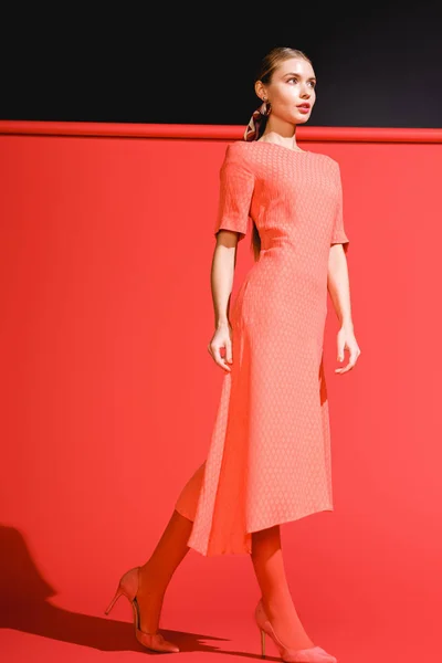 Brote de moda de niña posando en vestido de coral vivo sobre fondo rojo - foto de stock