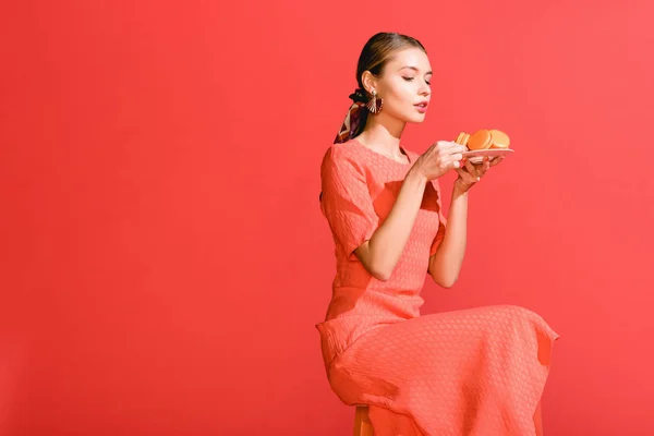 Donna alla moda che tiene il piatto con macaroni isolati su corallo vivo. Pantone colore dell'anno 2019 concept — Foto stock