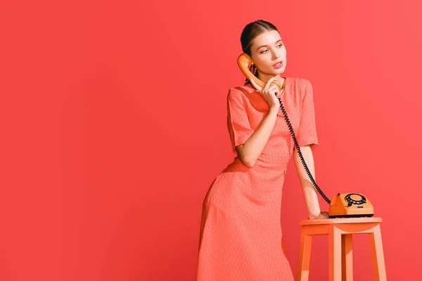 Mujer de moda con teléfono giratorio vintage aislado en coral vivo. Pantone color del año 2019 concepto - foto de stock