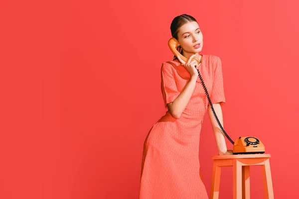 Femme à la mode avec téléphone rotatif vintage isolé sur corail vivant. Couleur Pantone de l'année 2019 concept — Photo de stock