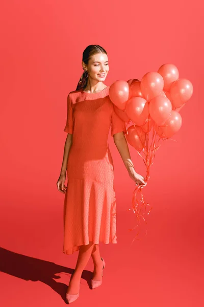 Souriant fille à la mode posant avec des ballons de corail vivant. Couleur Pantone de l'année 2019 concept — Photo de stock