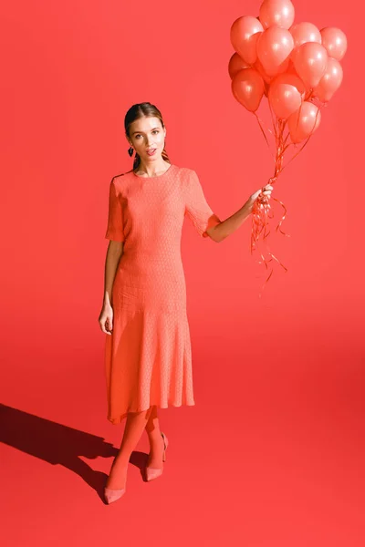 Giovane donna alla moda in posa con palloncini di corallo viventi. Pantone colore dell'anno 2019 concept — Foto stock