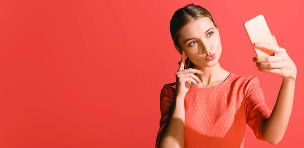 Belle fille élégante en robe de corail vivant prenant selfie sur smartphone sur rouge. Couleur Pantone de l'année 2019 concept — Photo de stock