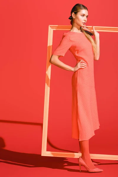 Modèle à la mode en robe posant avec grand cadre sur corail vivant. Couleur Pantone de l'année 2019 concept — Photo de stock