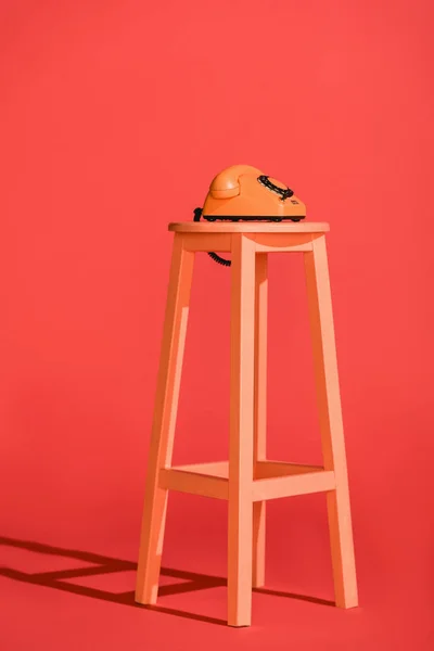 Living coral rotary telephone on stool. Pantone color of the year 2019 concept — Stock Photo