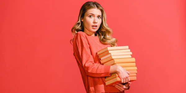 Shocked woman with books isolated on living coral. Pantone color of the year 2019 concept — Stock Photo