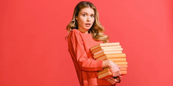 Femme choquée avec des livres isolés sur le corail vivant. Couleur Pantone de l'année 2019 concept — Photo de stock