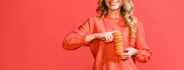 Vista recortada de la mujer sosteniendo macarrones dulces aislados en coral vivo. Pantone color del año 2019 concepto - foto de stock