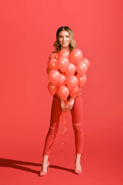 Smiling young woman posing with living coral balloons. Pantone color of the year 2019 concept — Stock Photo