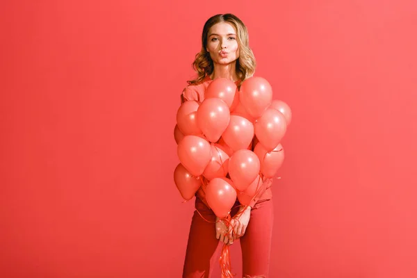 Menina atraente fazendo beijo de ar e posando com balões de coral vivos. Pantone cor do ano 2019 conceito — Fotografia de Stock