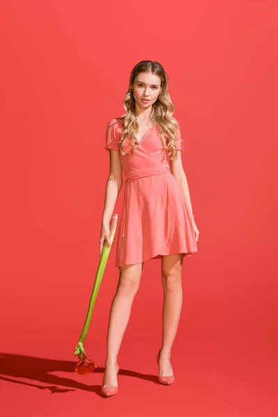 Beautiful woman in dress holding flower on living coral. Pantone color of the year 2019 concept — Stock Photo