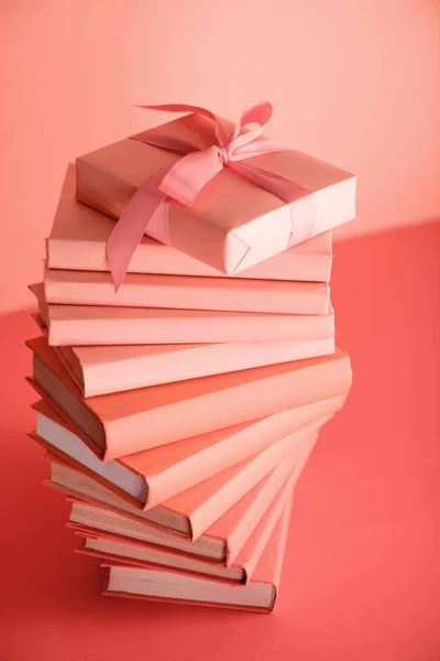 Pile de livres et cadeau d'anniversaire en couleur corail vivant. Couleur Pantone de l'année 2019 concept — Photo de stock