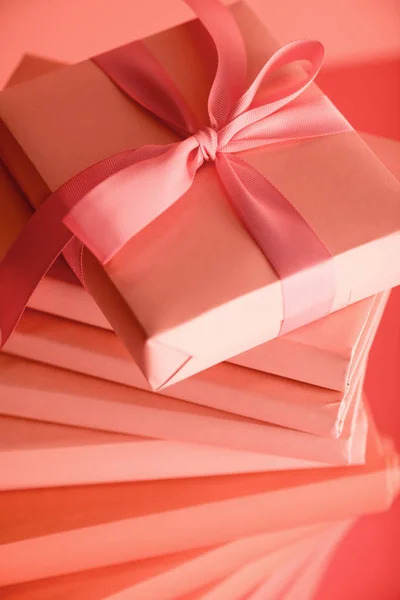 Close up of stack of books and gift box in living coral color. Pantone color of the year 2019 concept — Stock Photo