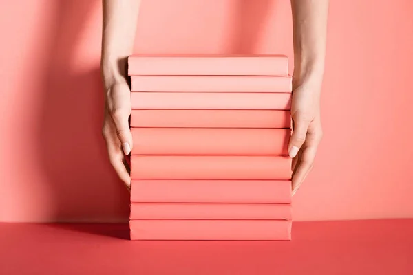 Partial view of female hands with living coral books. Pantone color of the year 2019 concept — Stock Photo