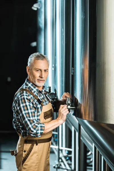 Professional senior male brewer working with brewery equipment — Stock Photo