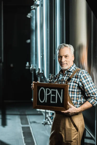 Successful senior owner holding board with open sign in brewery — Stock Photo