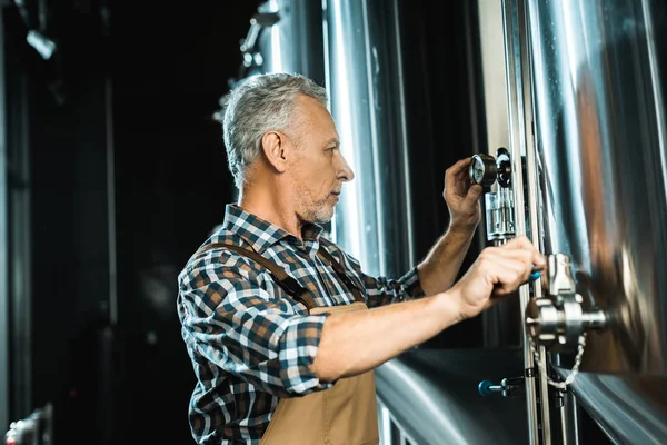 Cervejeiro sênior profissional que trabalha com equipamentos de cervejaria — Fotografia de Stock