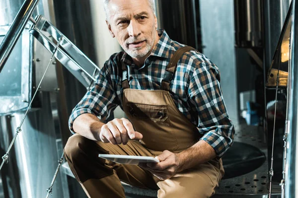 Male senior brewer using digital tablet in brewery — Stock Photo