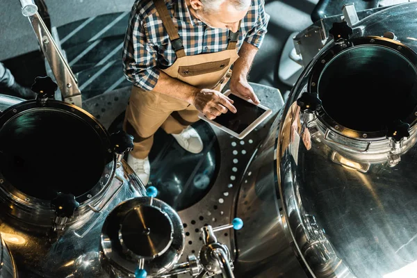 Overhead view of male brewer using digital tablet and working in brewery — Stock Photo
