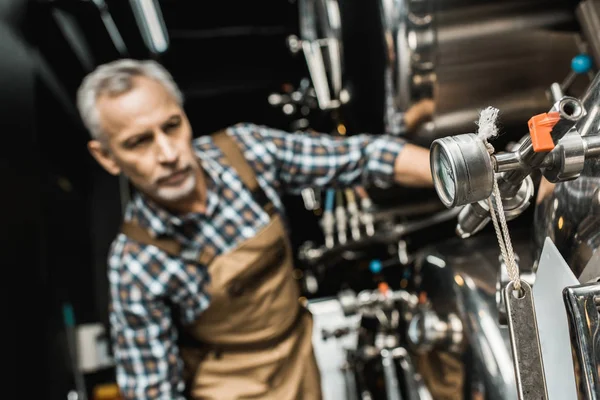 Focalizzazione selettiva del birraio professionista maschile che lavora con attrezzature per birrifici — Foto stock