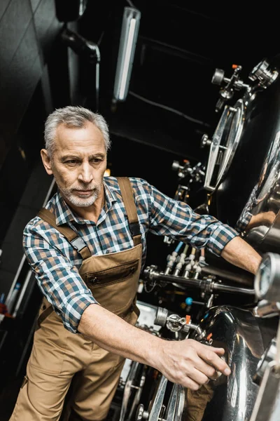 Handsome male brewer working with brewery equipment — Stock Photo