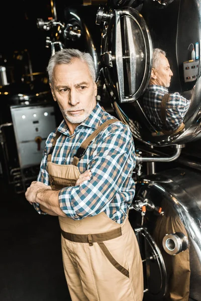 Professional senior brewer standing near brewery equipment — Stock Photo