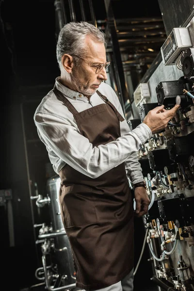 Birraio maschio professionale nel grembiule che controlla l'attrezzatura del birrificio — Foto stock