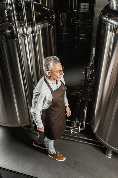 Male senior brewer in apron walking in brewery — Stock Photo