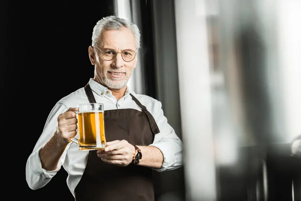 Brewer showing glass of beer in brewery — Stock Photo