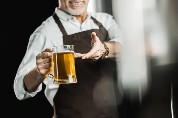 Vista recortada de la cervecera que muestra un vaso de cerveza en la cervecería - foto de stock