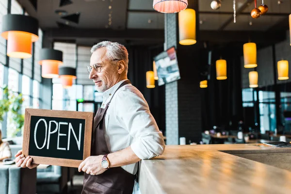 Kneipenbesitzer hält Schild offen und steht in der Nähe der Theke — Stockfoto