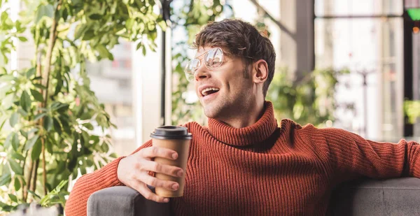 Jovem alegre em óculos segurando copo de papel no café — Fotografia de Stock