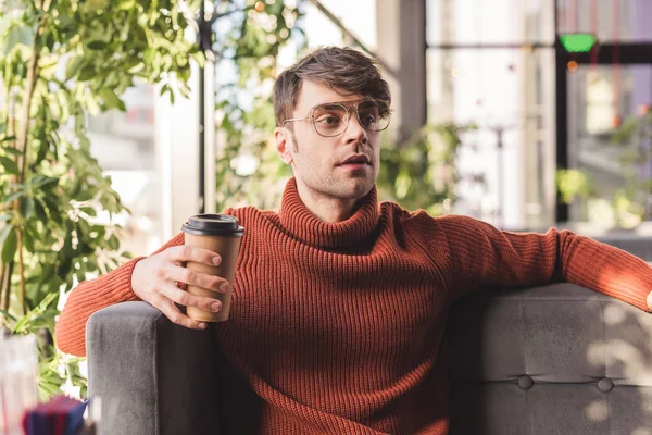 Bel homme dans des lunettes tenant tasse en papier dans un café — Photo de stock