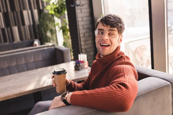 Homem feliz em óculos segurando copo de papel no café — Fotografia de Stock