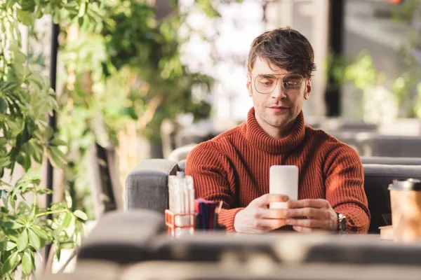 Cheerful man using smartphone near disposable cup in cafe — Stock Photo