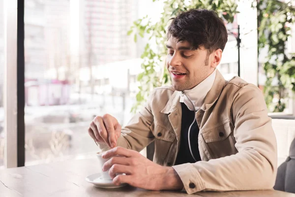 Homme gai regardant tasse avec cappuccino dans le café — Photo de stock