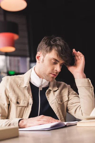 Hombre enfocado leyendo libro mientras está sentado en la cafetería - foto de stock