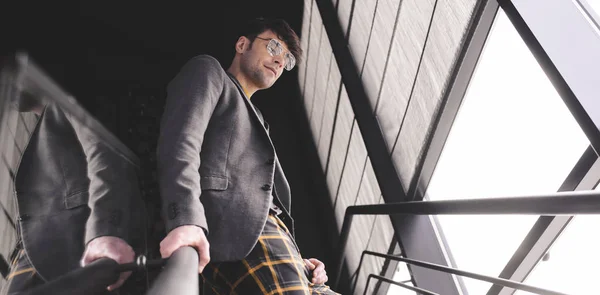 Stylish man in glasses standing on stairs — Stock Photo