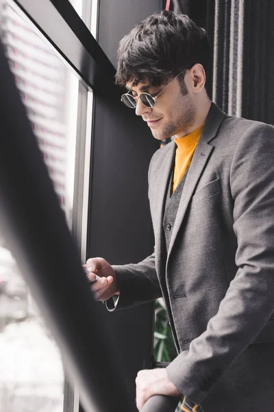 Selective focus of trendy young man in sunglasses standing on stairs — Stock Photo
